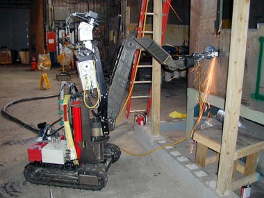 A Kraft Predator arm mounted on a mobile platform cutting a steel plate with an abrasive saw.